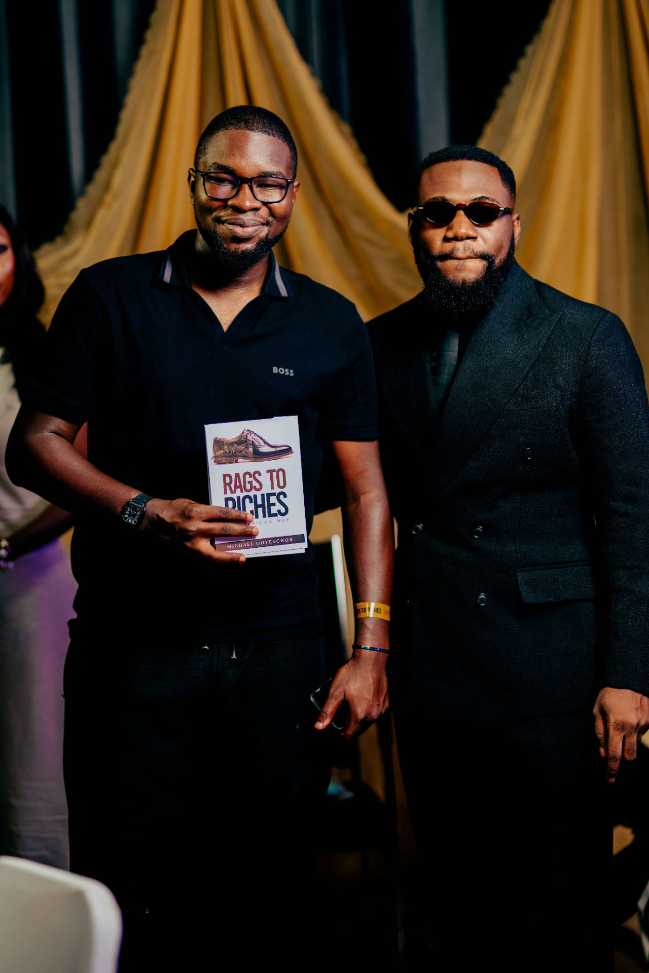 A guest holding a copy of Rags to Riches next to M.N. Onyeachor