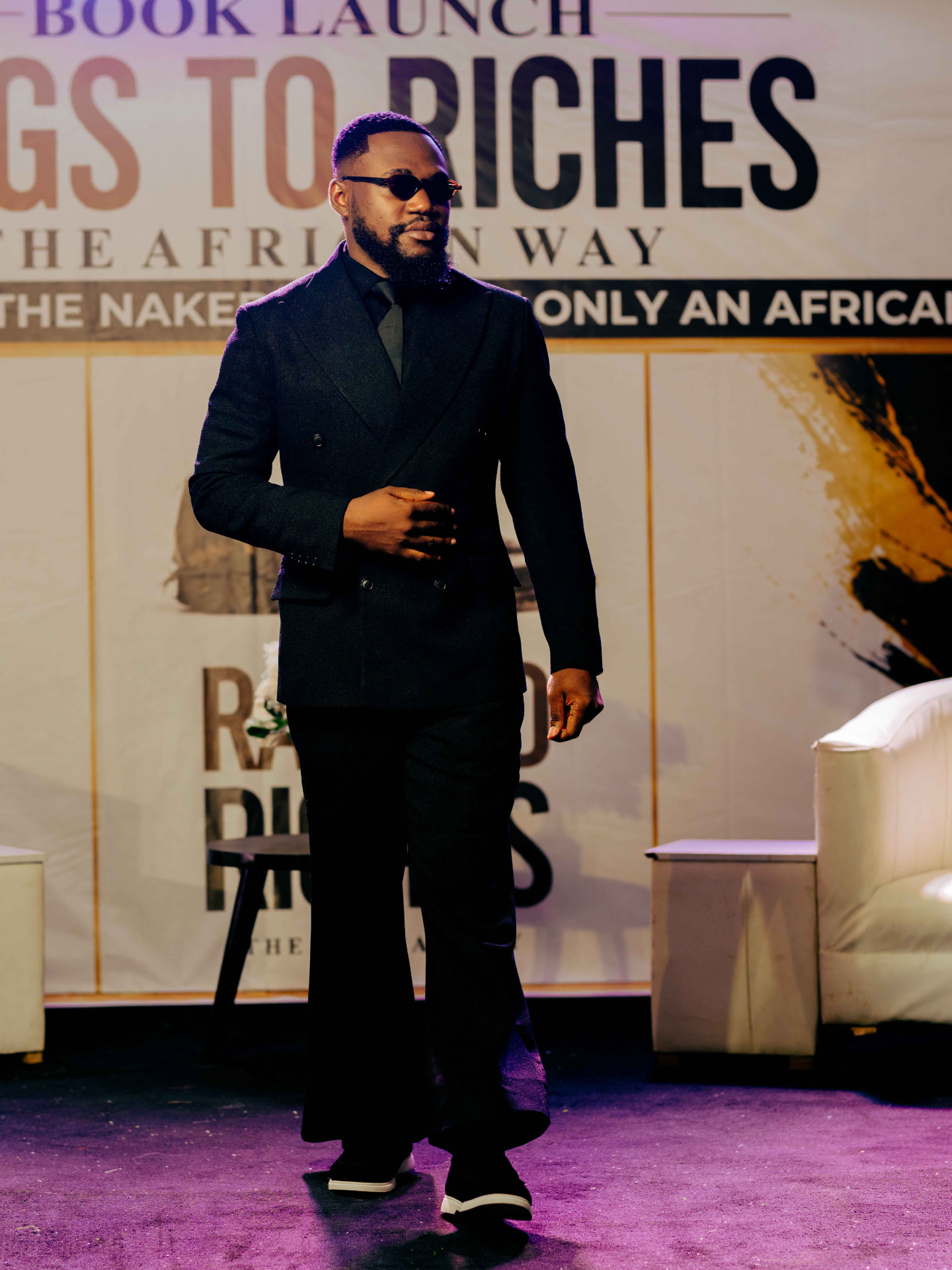 M.N. Onyeachor walking on stage in front of the book launch backdrop