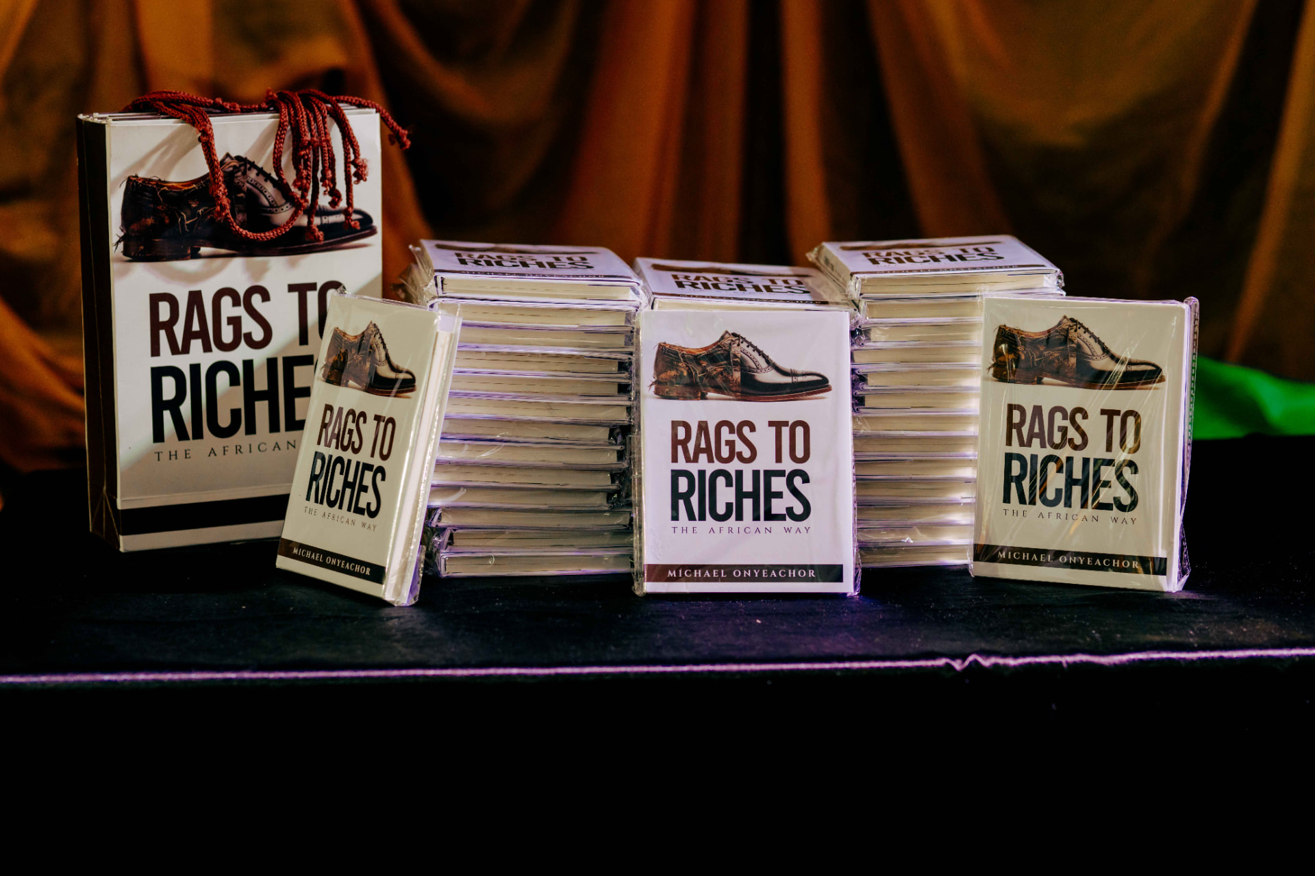 Stacked copies of Rags to Riches: The African Way on the sales table